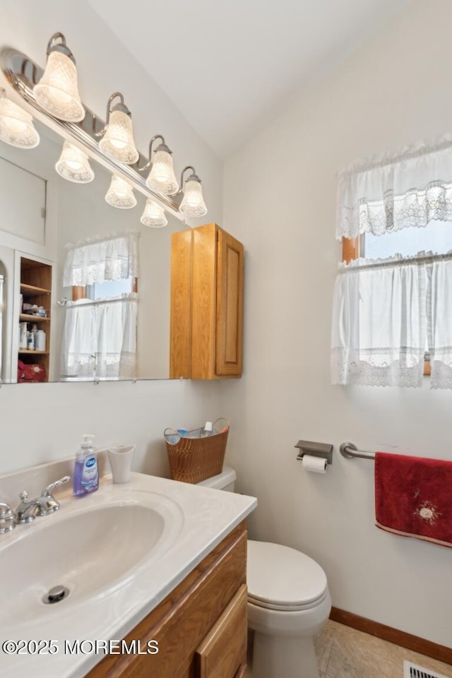 bathroom with vanity, lofted ceiling, tile patterned floors, and toilet