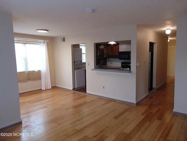 kitchen featuring dark brown cabinets, backsplash, light wood-type flooring, and electric stove