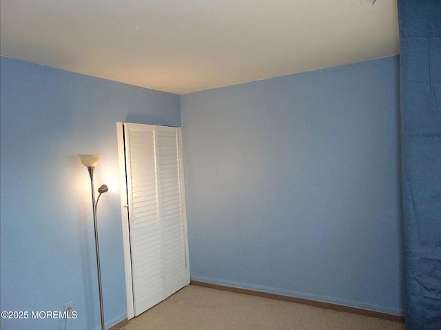 unfurnished bedroom featuring light carpet and a closet