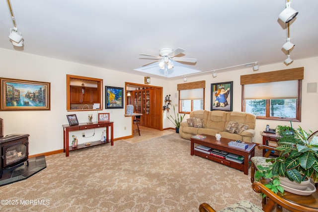 carpeted living room with rail lighting, a wood stove, and ceiling fan