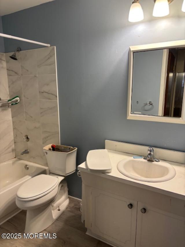 full bathroom with vanity, toilet, tiled shower / bath combo, and hardwood / wood-style floors