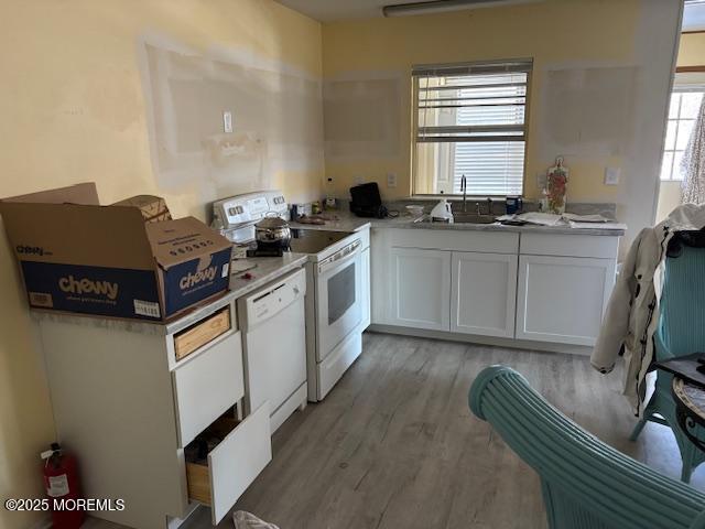 kitchen with sink, white cabinets, white appliances, and light wood-type flooring