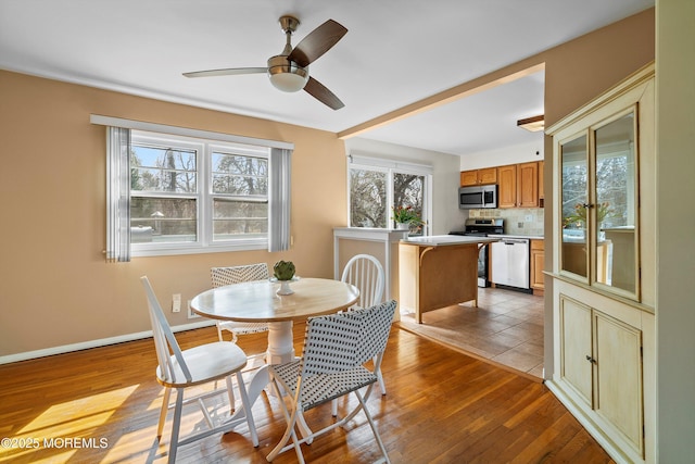 dining room with a ceiling fan, light wood-style flooring, and baseboards