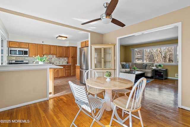 dining area featuring light wood-style flooring, baseboards, and ceiling fan