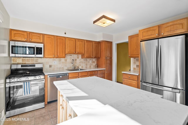 kitchen featuring brown cabinets, light tile patterned floors, tasteful backsplash, appliances with stainless steel finishes, and a sink