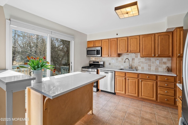 kitchen with appliances with stainless steel finishes, brown cabinetry, a sink, and tasteful backsplash