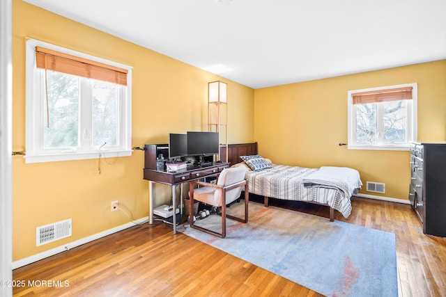 bedroom featuring baseboards, visible vents, and wood finished floors