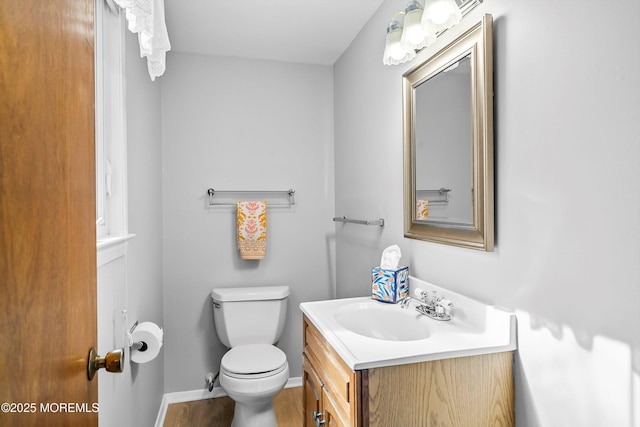 half bathroom featuring toilet, baseboards, and vanity