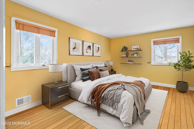 bedroom with light wood finished floors, baseboards, and visible vents