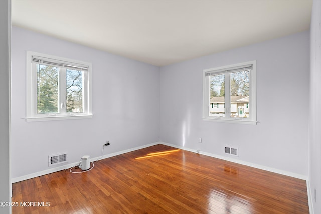 unfurnished room with hardwood / wood-style flooring, plenty of natural light, and visible vents