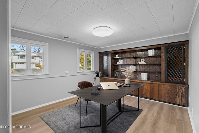 office featuring light wood finished floors, visible vents, baseboards, and crown molding