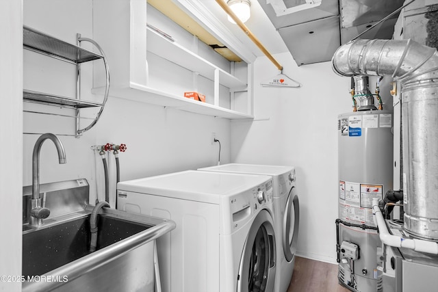 clothes washing area featuring dark wood finished floors, water heater, washing machine and dryer, a sink, and laundry area