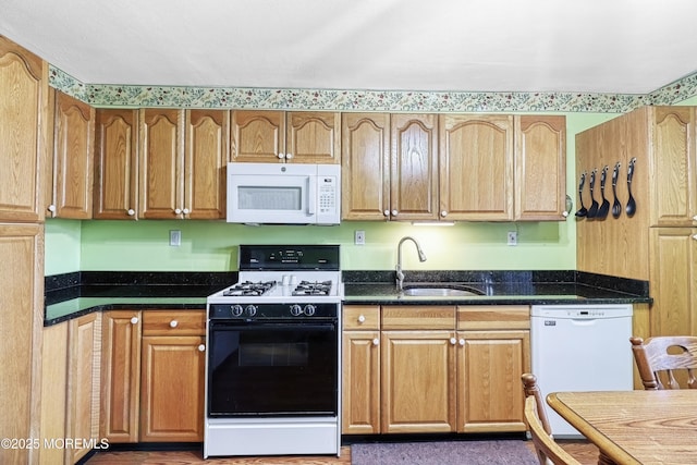 kitchen featuring sink, dark stone countertops, and white appliances