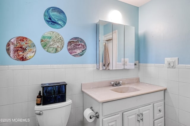 bathroom with vanity, toilet, and tile walls