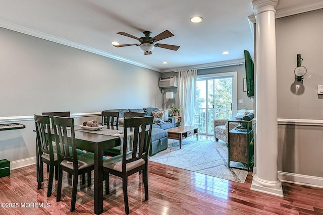 dining room featuring crown molding, a wall mounted AC, hardwood / wood-style floors, ceiling fan, and decorative columns