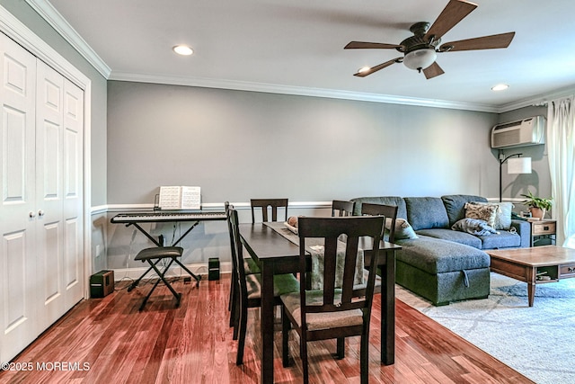 dining room featuring a wall mounted air conditioner, wood-type flooring, ornamental molding, and ceiling fan