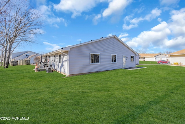 rear view of property with central AC unit and a lawn