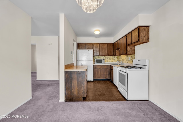 kitchen featuring sink, an inviting chandelier, white appliances, and dark carpet