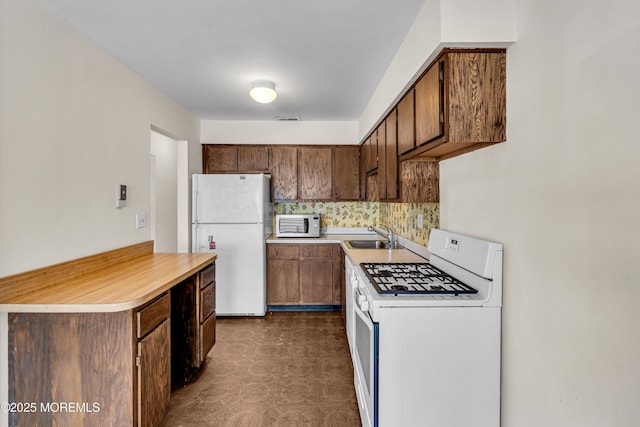 kitchen featuring sink, white appliances, and backsplash