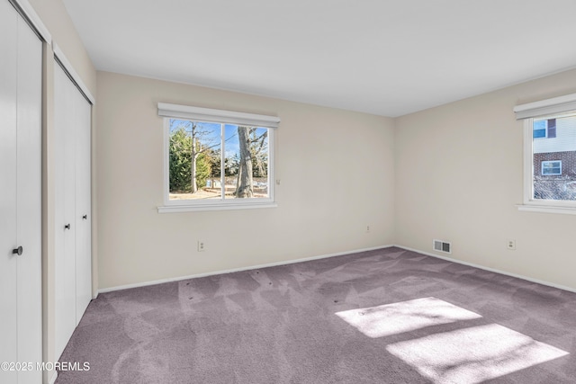 unfurnished bedroom with light colored carpet and a closet