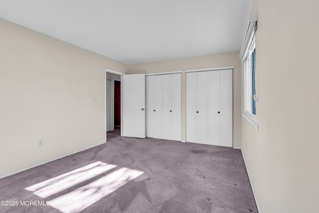 unfurnished bedroom featuring two closets and carpet