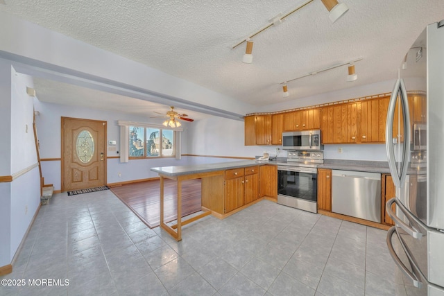 kitchen with appliances with stainless steel finishes, a kitchen bar, kitchen peninsula, and a textured ceiling