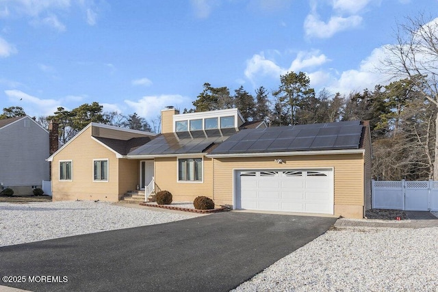 view of front facade with a garage and solar panels