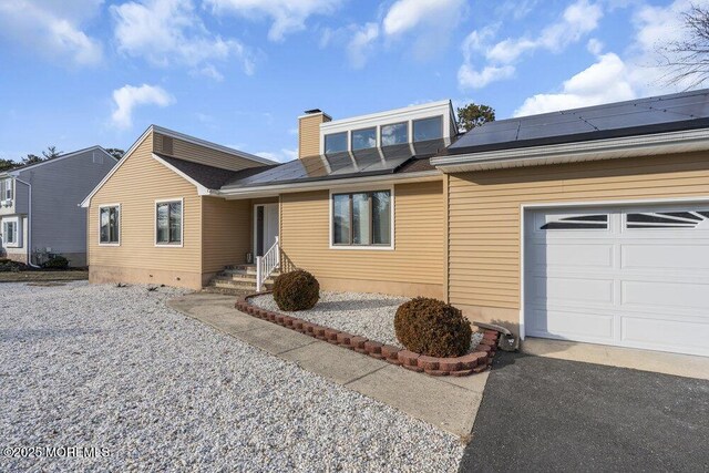 single story home with a garage and solar panels