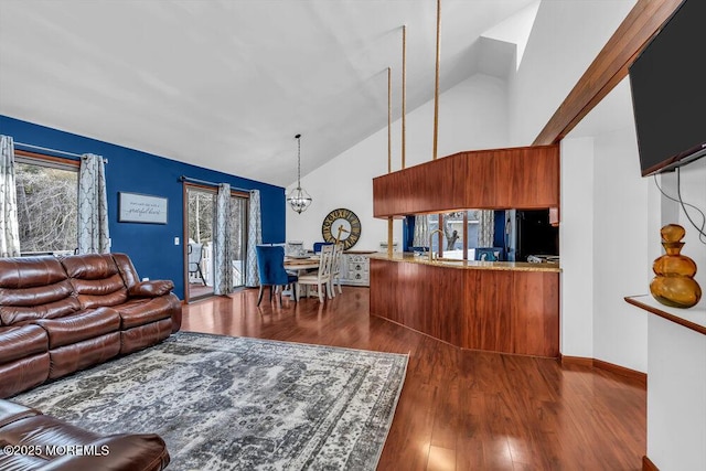 living room featuring dark hardwood / wood-style floors, sink, a notable chandelier, and high vaulted ceiling