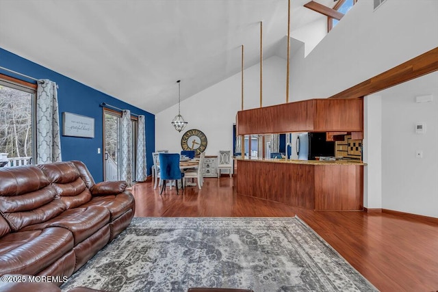 living room featuring a notable chandelier, dark wood-type flooring, and high vaulted ceiling