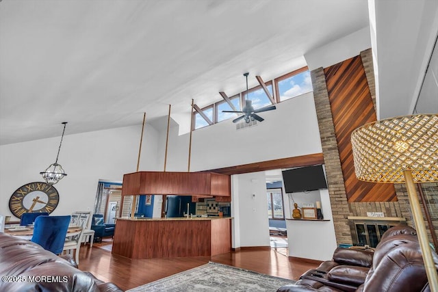 living room with a fireplace, high vaulted ceiling, dark hardwood / wood-style flooring, and ceiling fan with notable chandelier