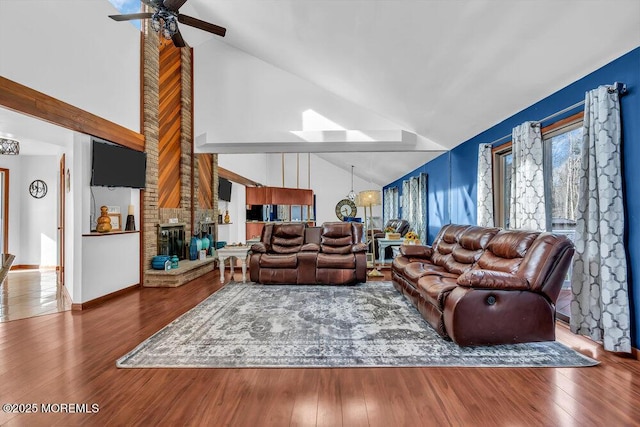 living room featuring ceiling fan, a fireplace, high vaulted ceiling, and wood-type flooring