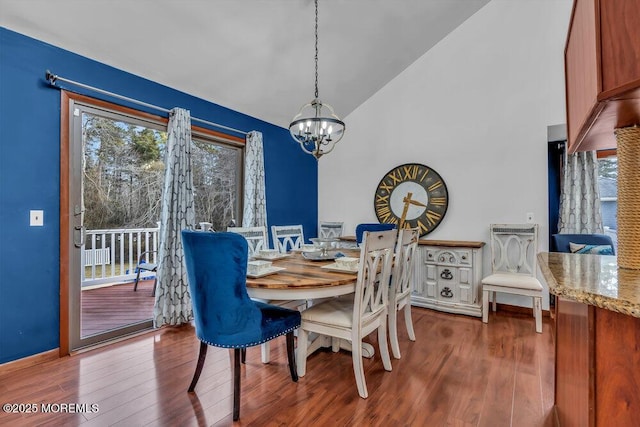 dining area with hardwood / wood-style floors, a notable chandelier, and high vaulted ceiling