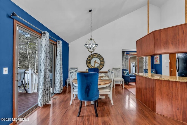 dining room with dark hardwood / wood-style flooring, high vaulted ceiling, and a chandelier