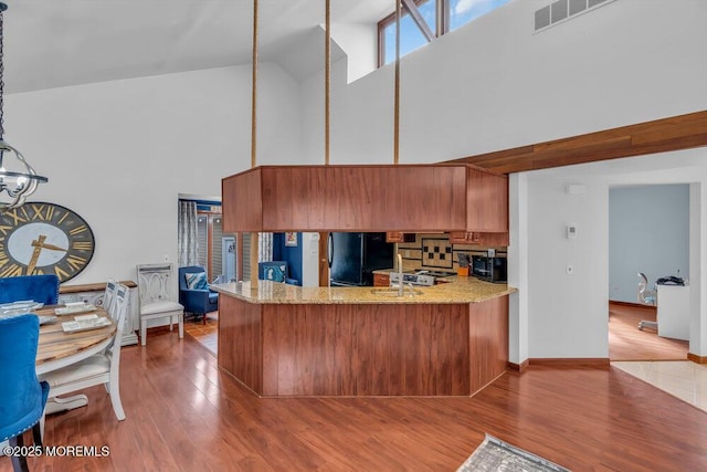 kitchen featuring hardwood / wood-style floors, hanging light fixtures, black appliances, and kitchen peninsula