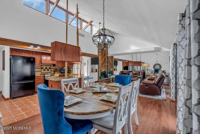 dining area featuring light hardwood / wood-style flooring, high vaulted ceiling, and a chandelier