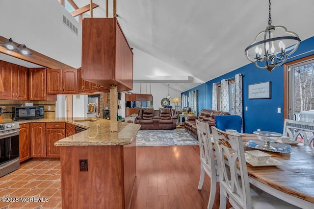 kitchen with sink, stainless steel range with electric cooktop, a chandelier, kitchen peninsula, and pendant lighting