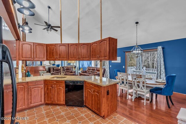 kitchen with sink, pendant lighting, light stone countertops, ceiling fan with notable chandelier, and black appliances