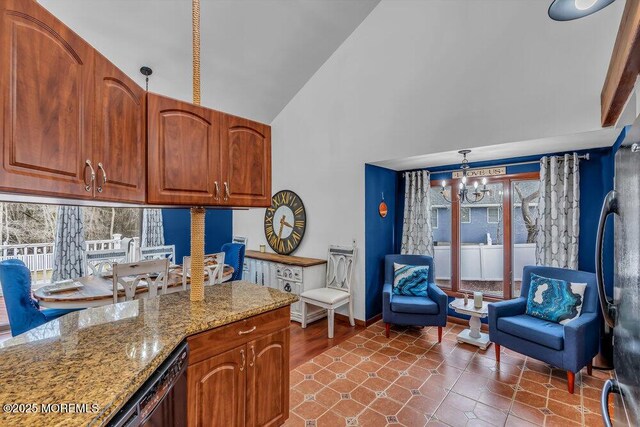 kitchen with pendant lighting, high vaulted ceiling, a chandelier, black appliances, and light stone countertops