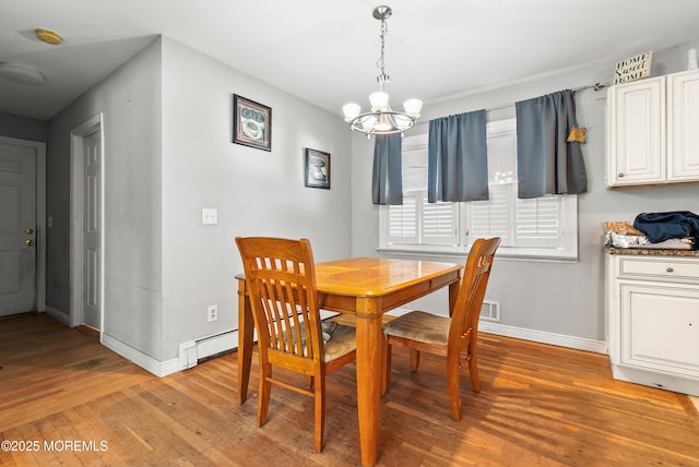 dining room featuring light wood-type flooring, a chandelier, and baseboard heating