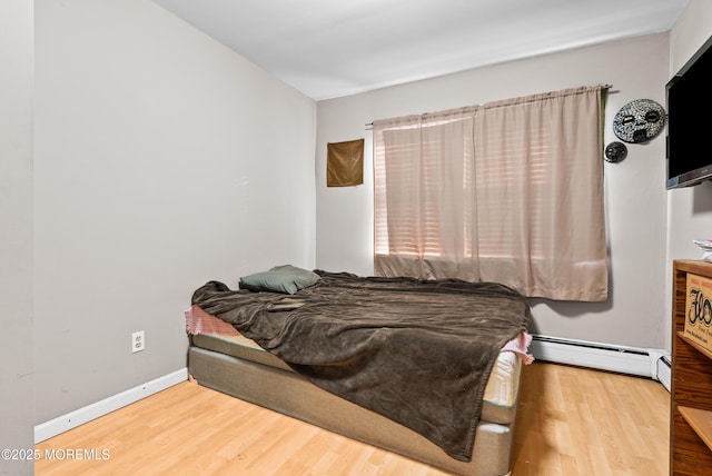 bedroom featuring wood-type flooring and a baseboard heating unit