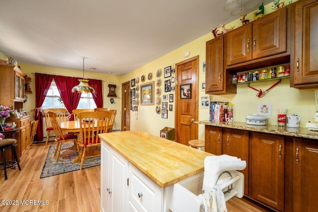 kitchen with pendant lighting, light hardwood / wood-style flooring, wood counters, and baseboard heating