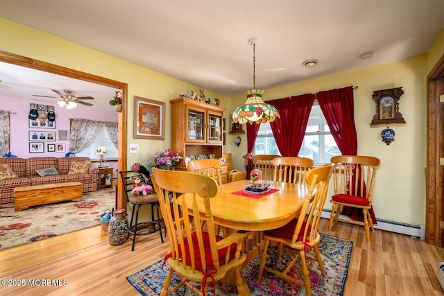 dining area featuring ceiling fan, a baseboard heating unit, and light wood-type flooring