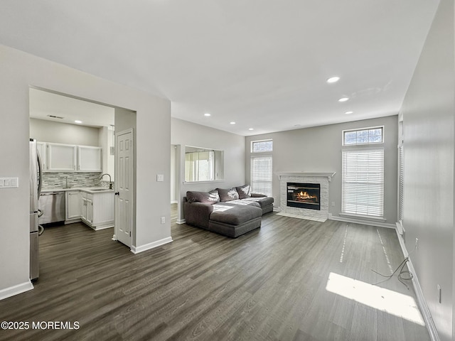 unfurnished living room with dark hardwood / wood-style floors, sink, and a wealth of natural light