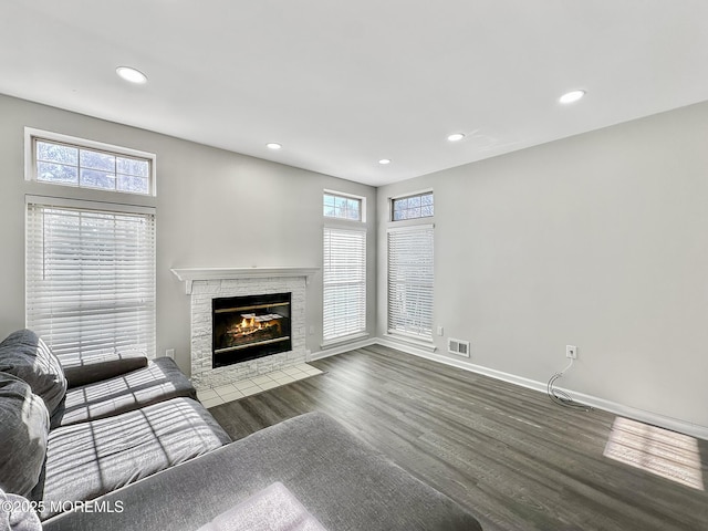 unfurnished living room featuring a wealth of natural light, a fireplace, and dark hardwood / wood-style flooring