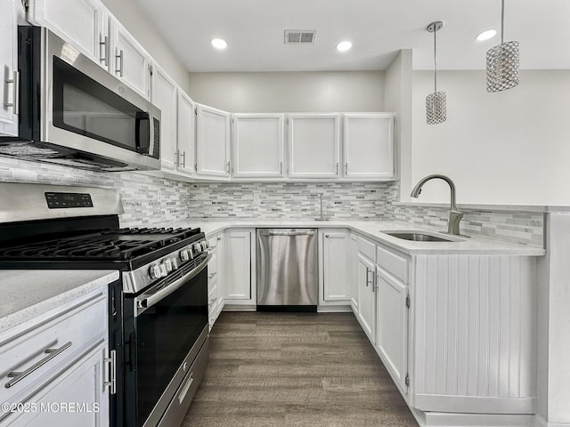 kitchen featuring pendant lighting, stainless steel appliances, sink, and white cabinets