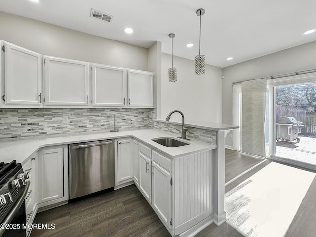 kitchen with appliances with stainless steel finishes, white cabinetry, sink, hanging light fixtures, and kitchen peninsula