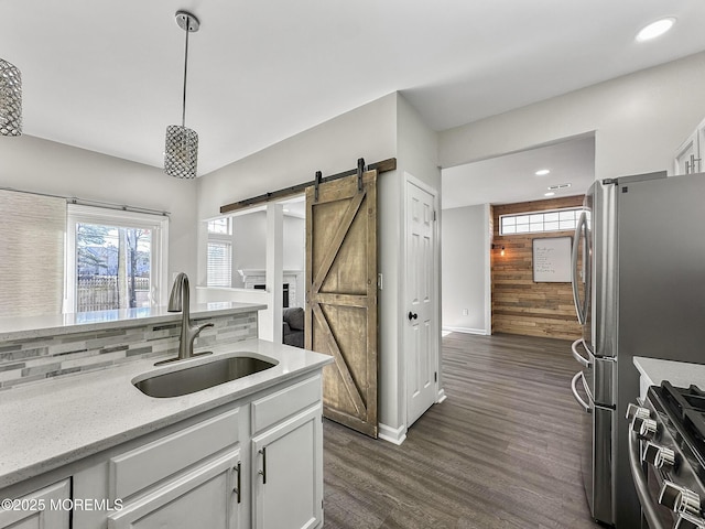 kitchen featuring sink, white cabinetry, hanging light fixtures, a barn door, and gas range oven