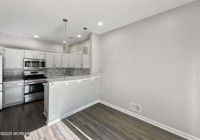 kitchen with a breakfast bar, pendant lighting, white cabinets, kitchen peninsula, and stainless steel appliances