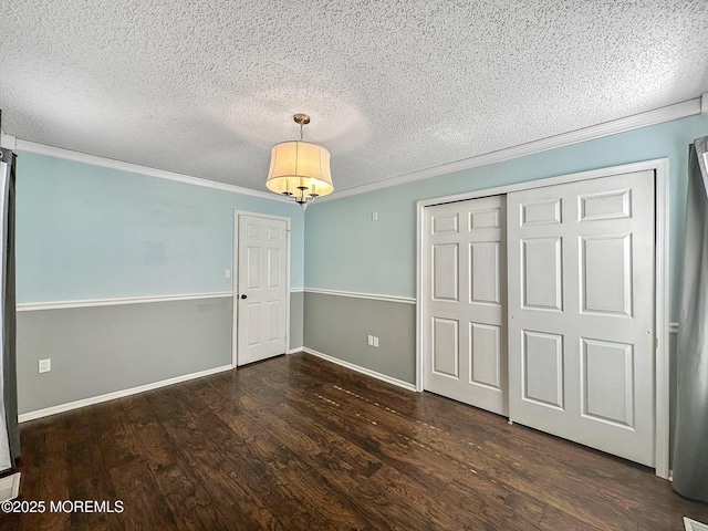 unfurnished bedroom with a closet, ornamental molding, dark hardwood / wood-style floors, and a textured ceiling